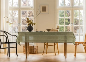Detail of light green tablecloth with white geometric embroidery on a wooden table