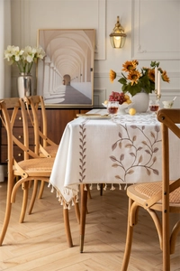 Detailed embroidery of brown coffee leaves on cream cotton linen tablecloth with fringe