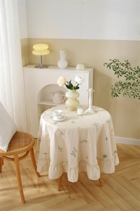 Detail of lavender embroidery on beige cotton tablecloth with pleated ruffle edges