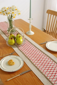 Detail of cotton linen table runner with red diamond embroidery and brown wavy borders