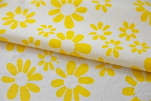 Detail of yellow daisy print on cotton fabric with visible fine woven texture and soft feel