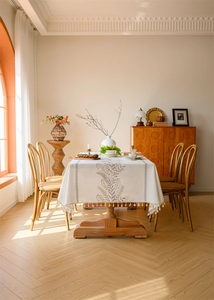 Detailed view of embroidery leaf patterns and tassel hem on beige rectangular tablecloth