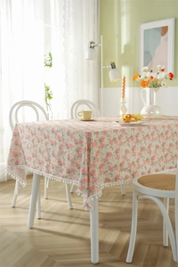Detail of pink floral cotton tablecloth featuring delicate white pom-pom fringe edges