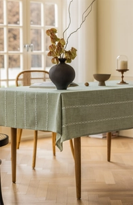 Detailed view of sage green jacquard tablecloth with white cross-line embroidery texture