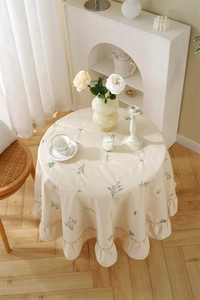 Detail of apricot cotton tablecloth featuring floral embroidery and ruffled edge design