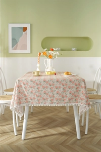Close-up of floral cotton tablecloth featuring orange rose prints and white pom-pom lace edge