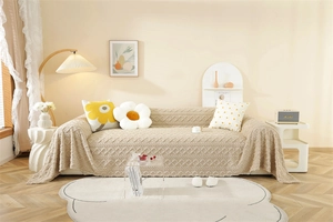 Detail of beige knitted textured sofa throw with 3D embossed jacquard weave pattern