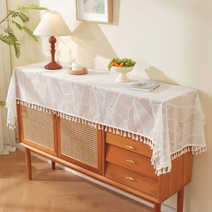 White French lace table runner with leaf patterns and tassels on a wooden cabinet
