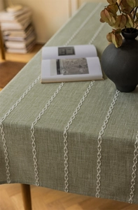 Macro detail of dark green jacquard tablecloth with white embroidered geometric patterns