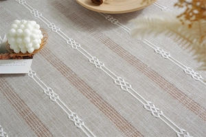Detailed close-up of beige polyester tablecloth with white embroidery and tassels