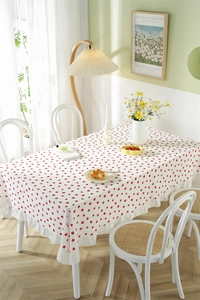 Detail of strawberry print cotton tablecloth with ruffled edges in a rustic dining room