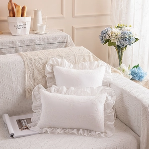 Detail of white cotton pillows with exquisite floral embroidery and ruffled edges