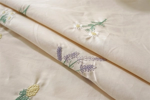 Detail of apricot cotton tablecloth with floral embroidery and elegant ruffled edges