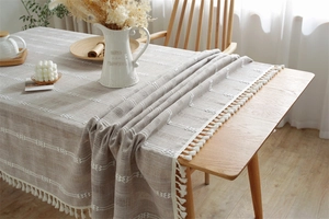 Close-up of geometric embroidery and elegant tassel edges on a beige jacquard tablecloth