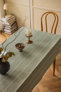 Macro detail of light green textured tablecloth with white wave pattern embroidery