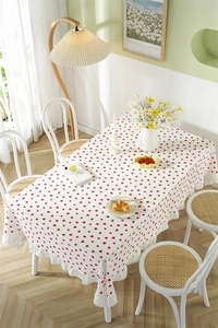 Close-up of strawberry print cotton tablecloth with ruffled edges and white pompoms