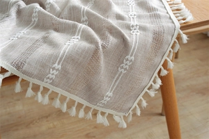 Detail of bohemian textured table runner with braided stripes and white tassel fringe