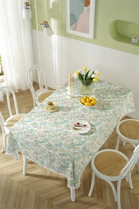 Detailed view of floral cotton tablecloth with delicate white pom-pom fringe trim