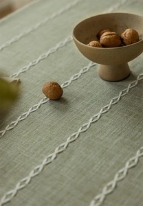 Detail of green linen table cloth showing white chain embroidery and woven texture