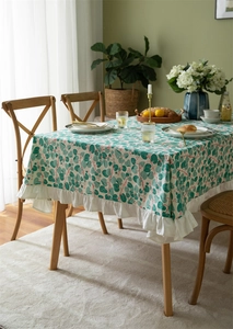 Detail of cotton tablecloth with green leaf print and elegant ruffled white edge trim
