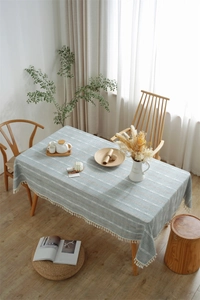 Close-up of grey-blue tablecloth with white jacquard stripes and fringe tassels