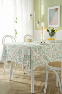 Close-up of floral cotton tablecloth with botanical print and white pom-pom trim