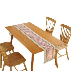 Cotton linen table runner with red geometric diamonds and fringe on a wooden table