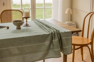 Detailed texture of dark green jacquard tablecloth with white geometric embroidery on wood table