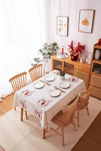 Detail of red floral wreaths and bow patterns on a cream rectangular cotton tablecloth