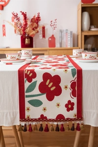 Detailopname van de bruiloftstafelloper met rode bloemmotieven en decoratieve kwastjes