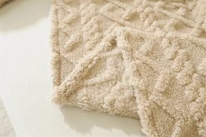Close-up of thick plush throw blanket showing soft beige textured jacquard pattern
