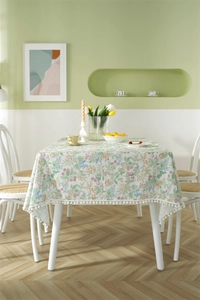 Detail of floral berry pattern tablecloth featuring white pom-pom fringe trim