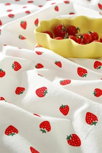 Close-up of cotton tablecloth with red strawberry print and detailed ruffle edges