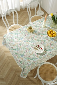 Close-up of floral cotton tablecloth with white pom-pom trim and botanical berry patterns