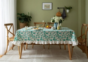 Detail of cotton floral tablecloth featuring fresh green leaf patterns and ruffled edges