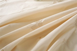 Detail of floral embroidery and ruffled edge on cream cotton round tablecloth fabric