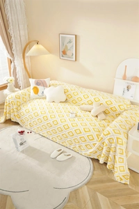 Detail of yellow and white geometric diamond pattern plush sofa throw with soft texture
