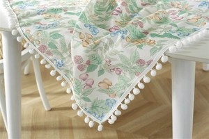 Detailed view of floral berry print tablecloth with white pom-pom fringe trim edges