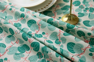 Close-up of cotton floral tablecloth showing green leaf prints and soft fabric texture