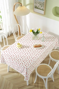 Close-up of strawberry print cotton tablecloth featuring white pom-pom fringe edges