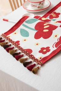 Detail van bloemmotief jacquard tafelloper met decoratieve kleurrijke kwastjes