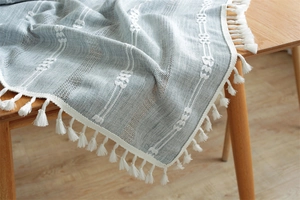 Macro detail of Nordic blue textured table runner with white fringe on wooden surface