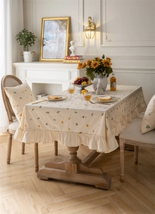 Close-up of beige cotton tablecloth with yellow floral pattern and ruffled edges