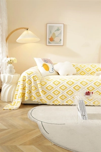Detailed knit texture of a thick yellow and white geometric diamond pattern sofa cover