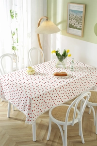 Detailed view of white strawberry floral tablecloth with decorative white pom-pom fringe