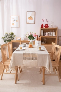 Detail of beige cotton linen tablecloth with crochet lace insert and elegant tassels