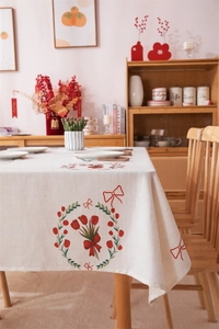 Detailed close-up of cream rectangular tablecloth with red tulip wreath and bow prints