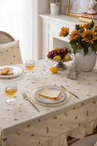 Detailed close-up of apricot cotton tablecloth with floral embroidery and ruffled edge design