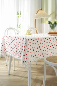 Detail of white cotton tablecloth with strawberry print and white pom-pom fringe trim