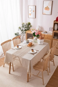 Detail of linen tablecloth with fringe and lace runner in a minimalist Nordic dining setting